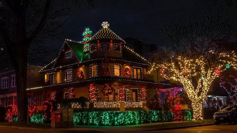 Multi-story wooden house wrapped in colorful Christmas lights at night