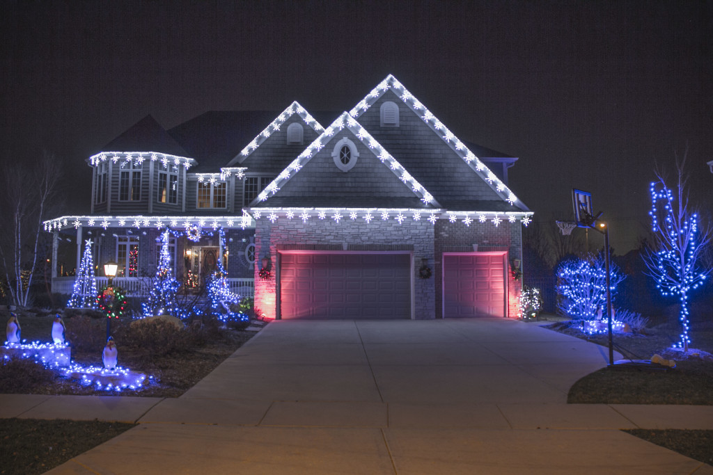 Two-story home with blue and white Christmas lights over the garage at night