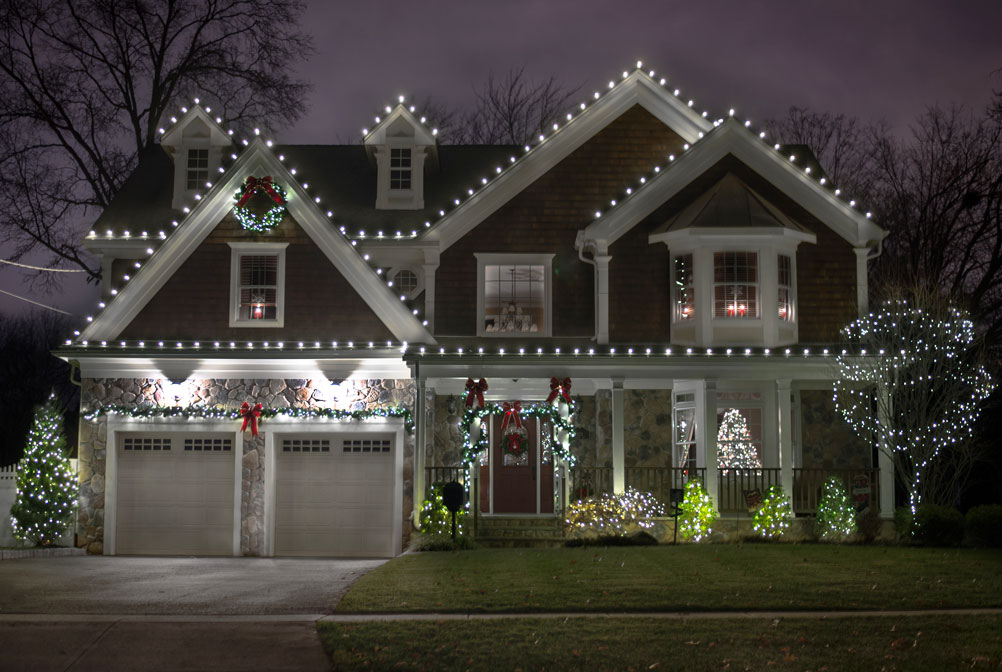 Gray two-story home with white Christmas lights along the roof and garage